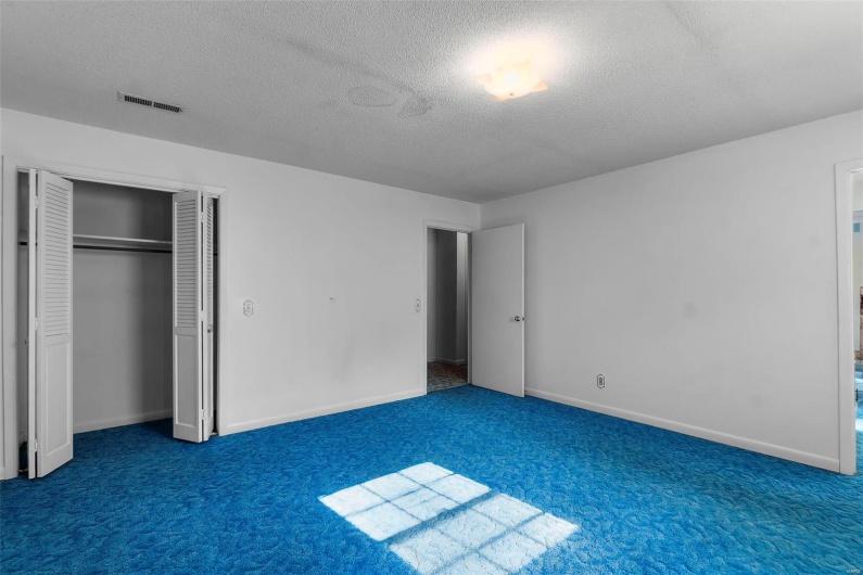 Unfurnished bedroom with visible vents, carpet flooring, a textured ceiling, and a closet