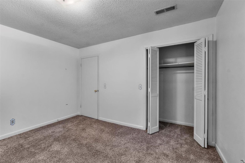 Unfurnished bedroom featuring visible vents, a closet, baseboards, a textured ceiling, and carpet flooring