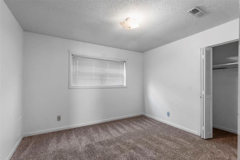 Unfurnished bedroom with carpet floors, a closet, a textured ceiling, and visible vents