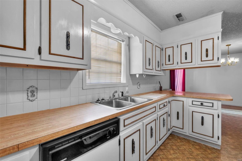 Kitchen with a sink, dishwasher, a textured ceiling, a peninsula, and decorative backsplash