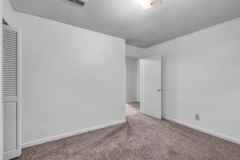 Unfurnished room featuring carpet floors, baseboards, a textured ceiling, and visible vents