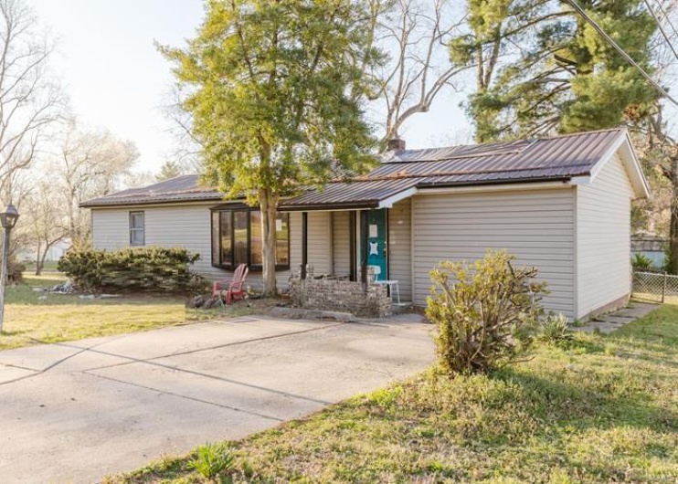 Single story home featuring metal roof and a front yard