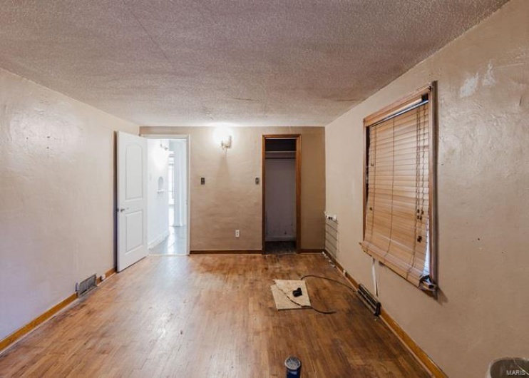 Unfurnished room featuring a textured ceiling, baseboards, and wood finished floors