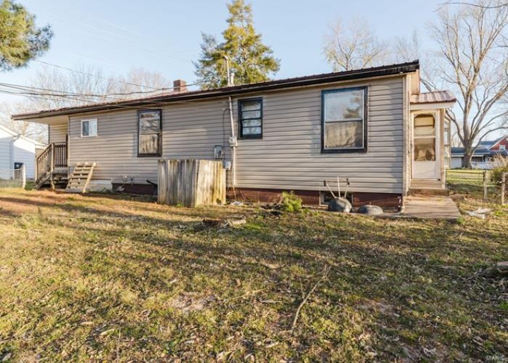 Back of property with a lawn and fence