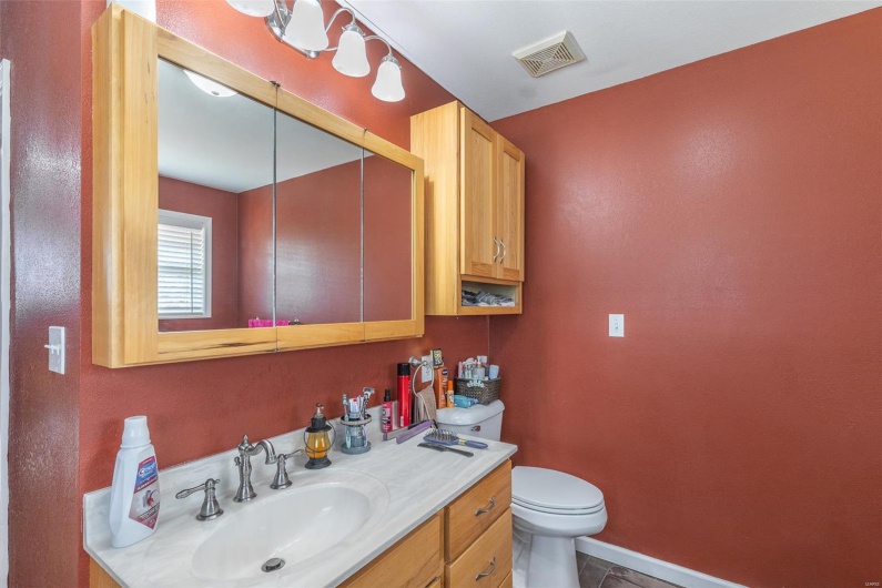 Bathroom with toilet, baseboards, visible vents, and vanity