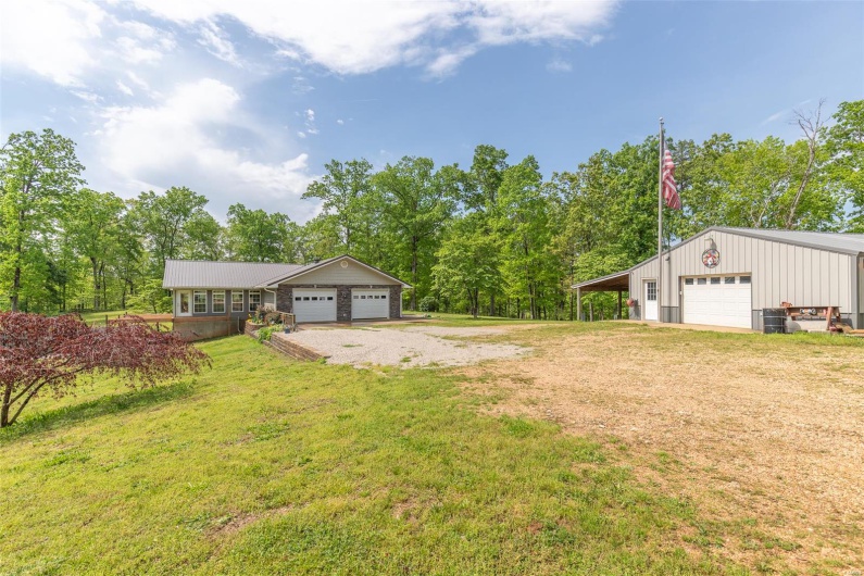 View of yard with a detached garage, an outbuilding, and driveway