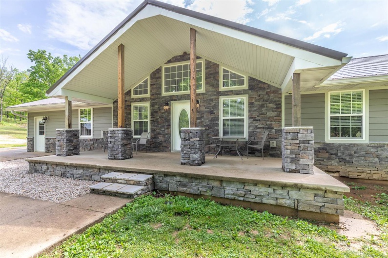 Rear view of house featuring covered porch and stone siding