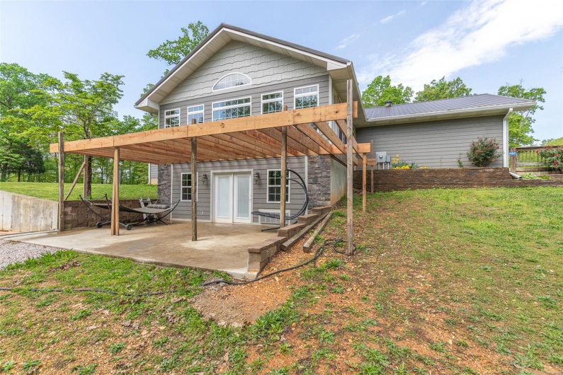 Back of property with a lawn, a patio area, and metal roof