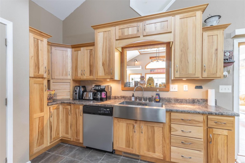 Kitchen featuring dishwasher, vaulted ceiling, and light brown cabinets
