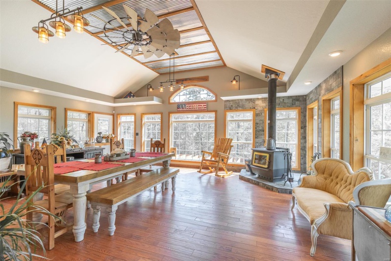 Dining area featuring a ceiling fan, wood-type flooring, a wood stove, and lofted ceiling
