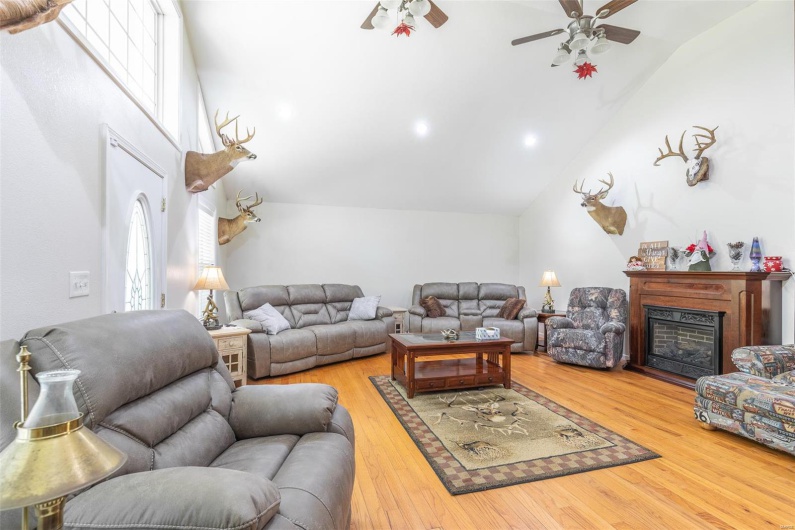 Living area with a ceiling fan, vaulted ceiling, hardwood / wood-style flooring, and a fireplace