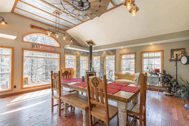 Dining space featuring baseboards, a wood stove, hardwood / wood-style flooring, and high vaulted ceiling