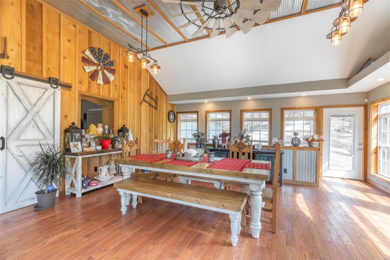 Dining room featuring high vaulted ceiling, plenty of natural light, wood walls, and light wood-type flooring