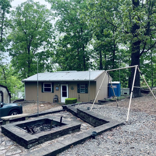 View of front of house with a playground, board and batten siding, an outdoor fire pit, and metal roof
