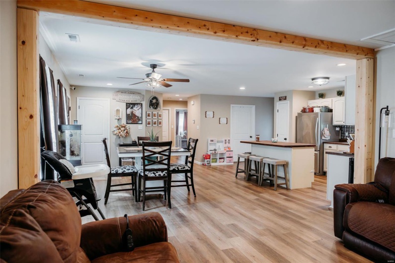 Living room with light wood-style floors, a ceiling fan, recessed lighting, beamed ceiling, and visible vents