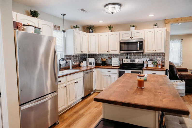 Kitchen featuring visible vents, tasteful backsplash, a sink, wood counters, and appliances with stainless steel finishes