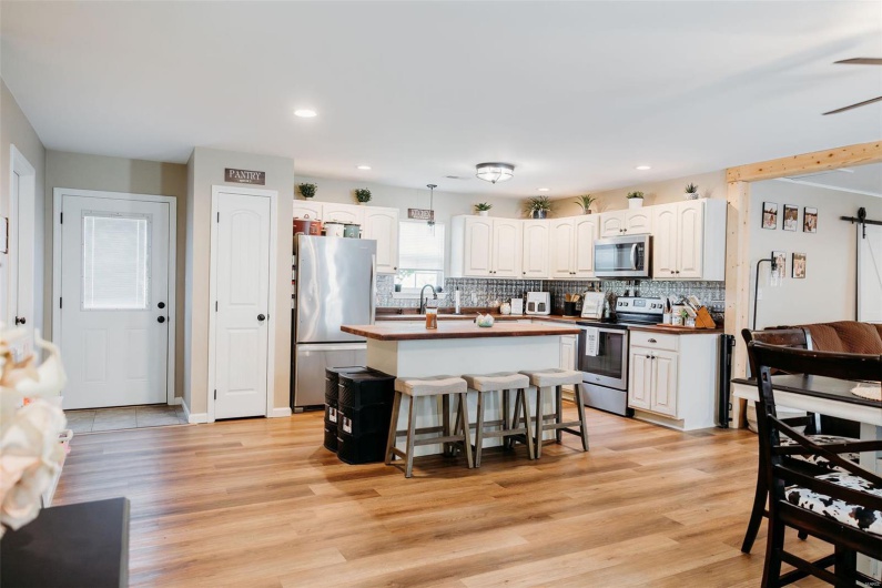 Kitchen featuring white cabinetry, butcher block countertops, appliances with stainless steel finishes, and tasteful backsplash
