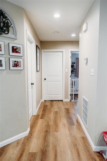 Hallway with light wood-style floors, baseboards, recessed lighting, and visible vents