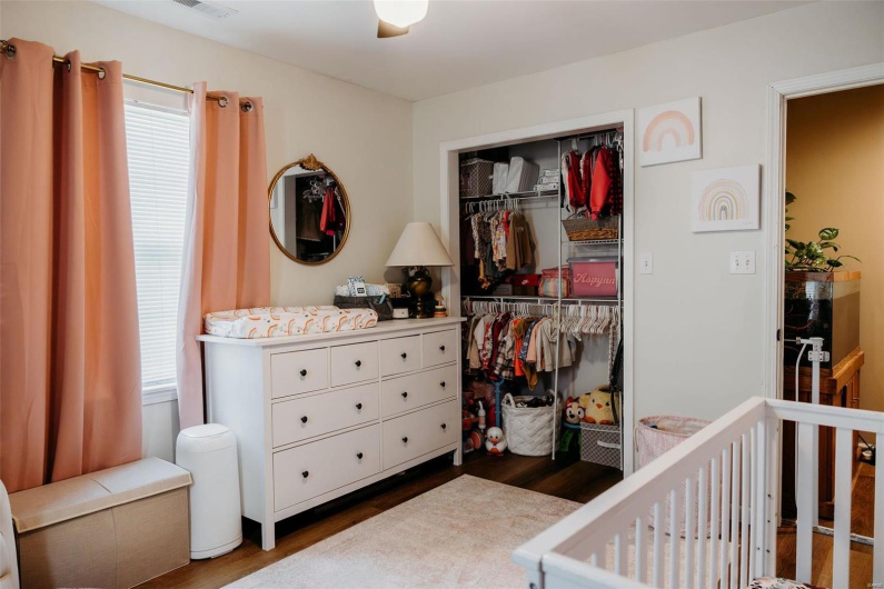 Bedroom with a closet, a crib, wood finished floors, and multiple windows