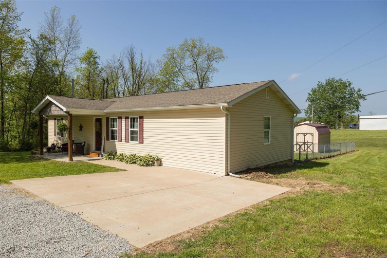 Ranch-style home featuring a front lawn, a shed, an outbuilding, a patio area, and driveway