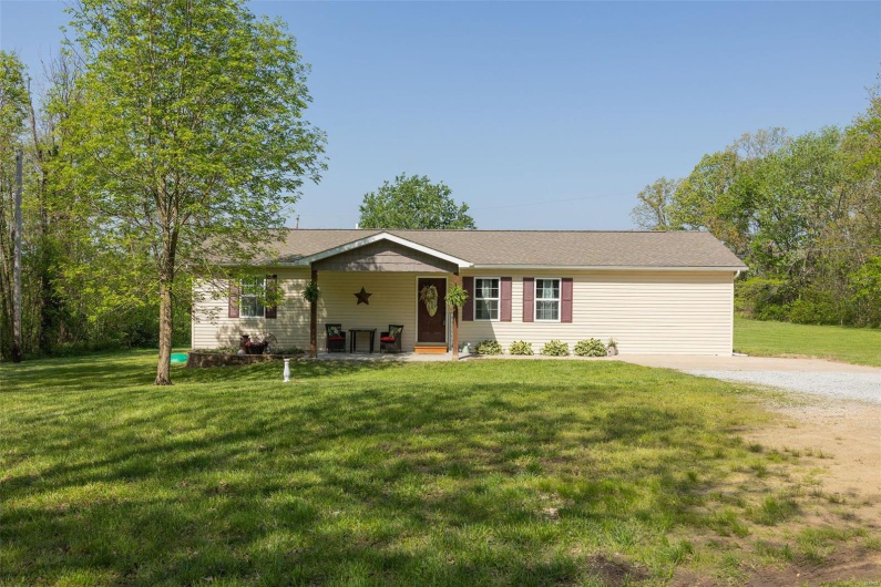 Ranch-style home with covered porch, driveway, and a front yard