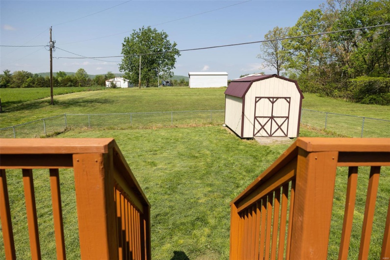 View of yard featuring a rural view, an outbuilding, a shed, and a fenced backyard
