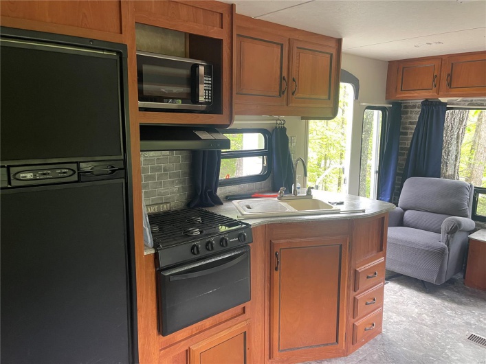 Kitchen with plenty of natural light, a sink, stainless steel microwave, and black refrigerator