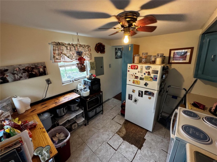Kitchen featuring a ceiling fan, white appliances, light tile patterned flooring, and electric panel