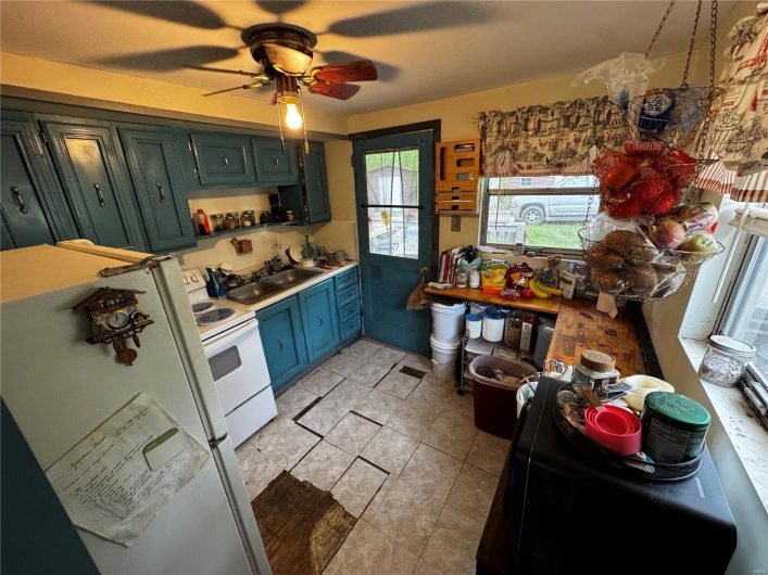 Kitchen with a sink, white appliances, light countertops, and a ceiling fan