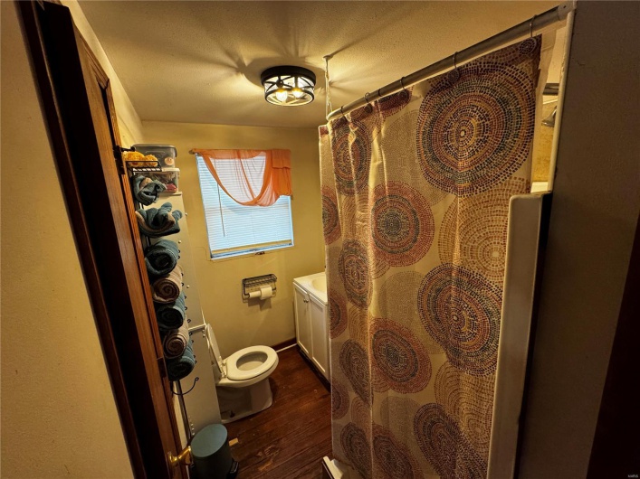 Full bath featuring toilet, a shower with curtain, and wood finished floors