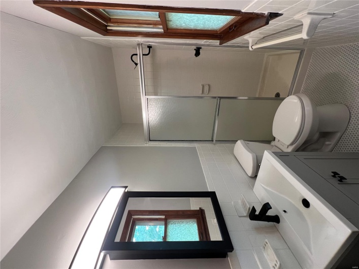 Bathroom featuring a stall shower, tile walls, toilet, tile patterned floors, and vanity