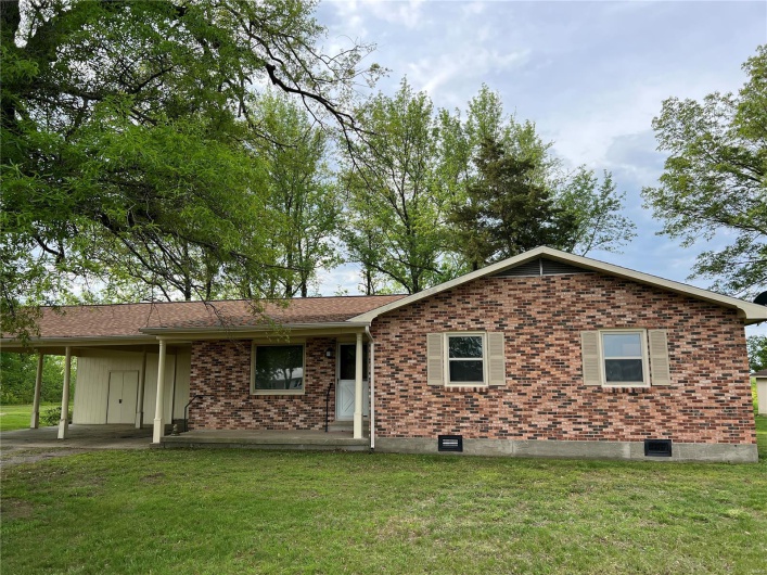 View of front of home featuring brick siding, a front yard, and an attached carport