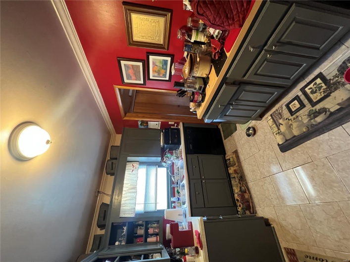 Kitchen with dishwashing machine, light tile patterned floors, a sink, light countertops, and ornamental molding