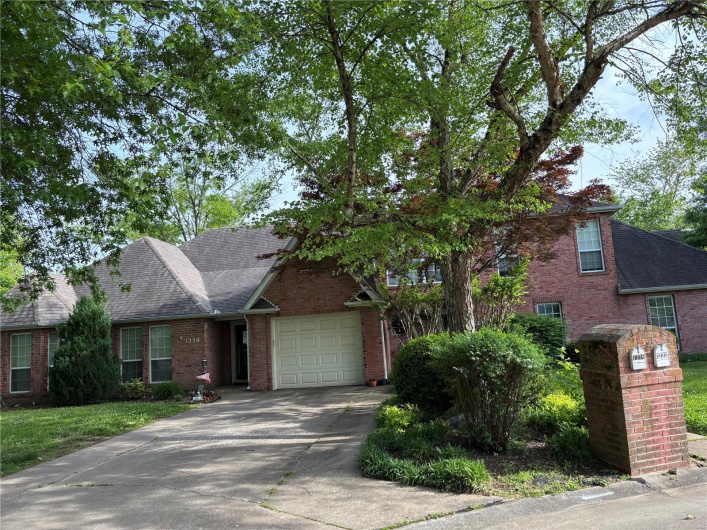 View of front of property with brick siding, concrete driveway, a garage, and roof with shingles