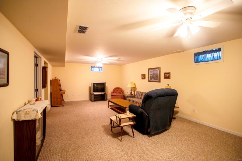 Living area with carpet, visible vents, baseboards, and a ceiling fan