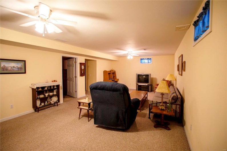 Living room with ceiling fan, light carpet, baseboards, and visible vents