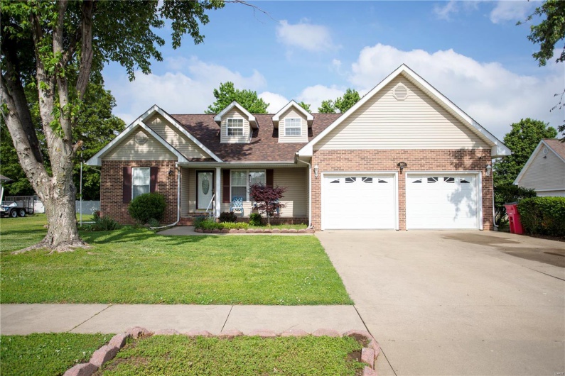 View of front of house featuring an attached garage, concrete driveway, a porch, a front yard, and brick siding