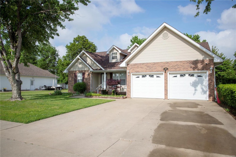 View of front facade featuring a garage, brick siding, driveway, and a front yard