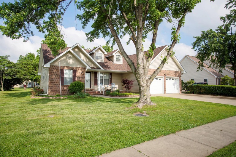 View of front of home featuring concrete driveway, brick siding, a front lawn, and a garage