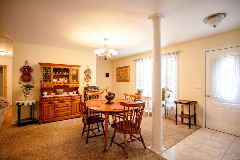 Dining room featuring light tile patterned floors, a notable chandelier, light carpet, and ornate columns