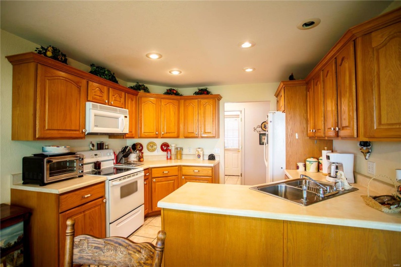 Kitchen with brown cabinetry, a sink, and white appliances