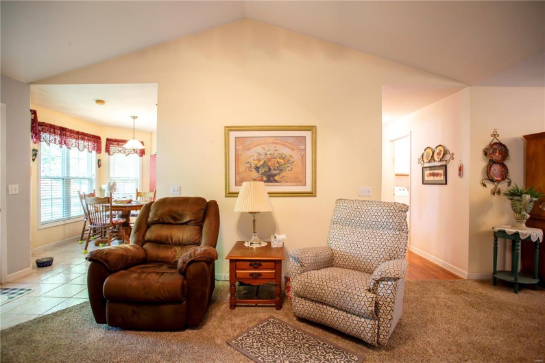 Sitting room with carpet floors, baseboards, lofted ceiling, and a notable chandelier