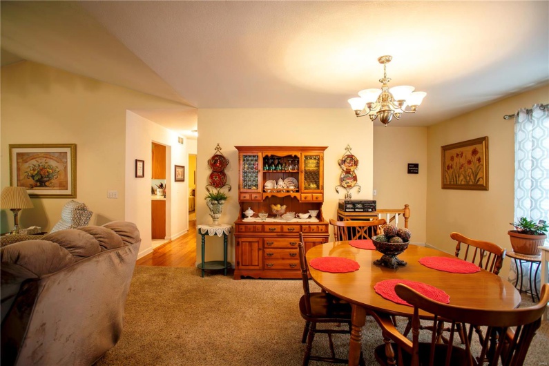 Dining area with light colored carpet, a chandelier, and lofted ceiling