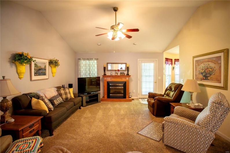 Carpeted living area featuring baseboards, a glass covered fireplace, ceiling fan, and high vaulted ceiling