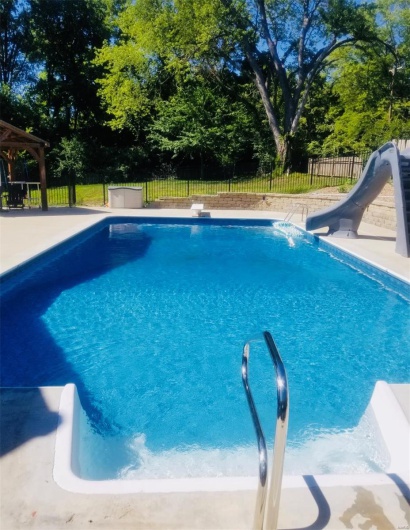 View of pool with a water slide, a fenced backyard, a gazebo, and a diving board
