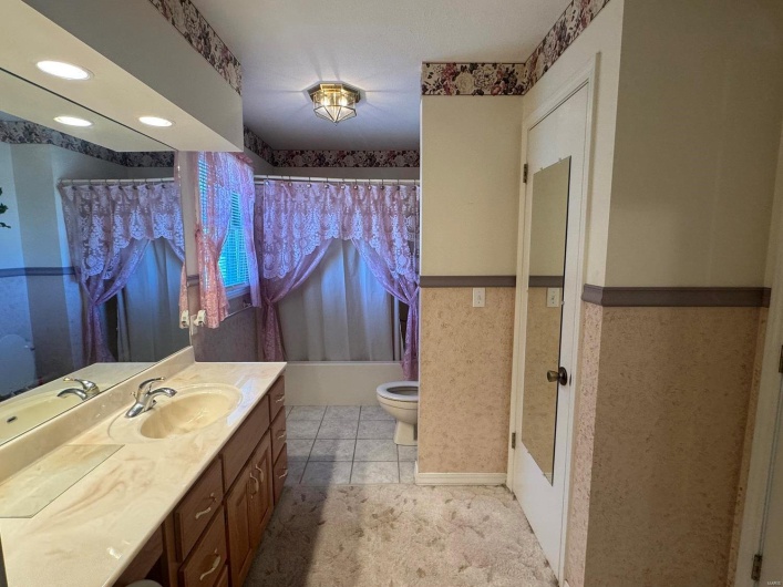 Full bathroom featuring shower / tub combo, tile patterned floors, vanity, and toilet