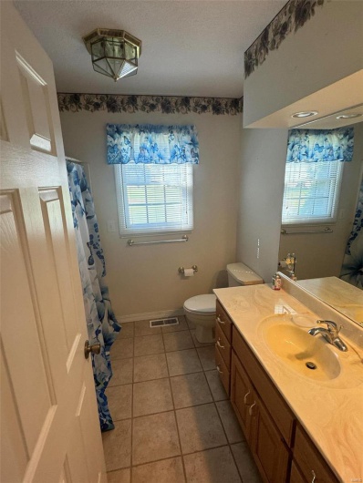 Bathroom featuring a healthy amount of sunlight, tile patterned floors, vanity, and toilet