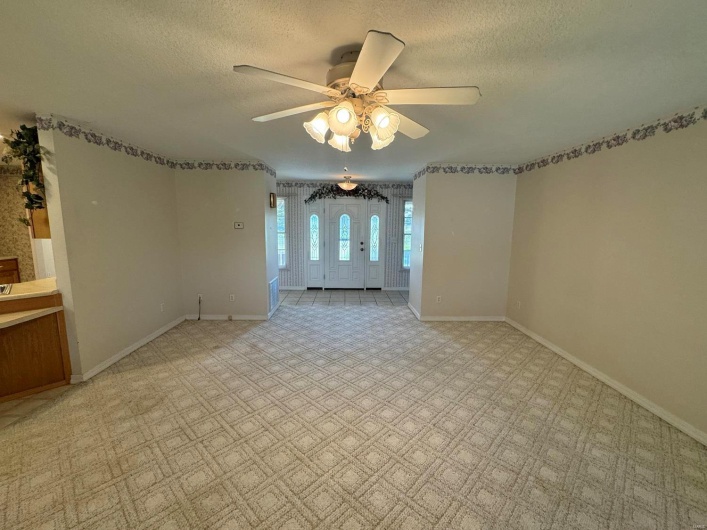 Carpeted spare room featuring ceiling fan and a textured ceiling