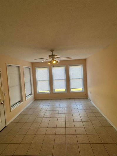 Unfurnished room featuring plenty of natural light, light tile patterned floors, and ceiling fan
