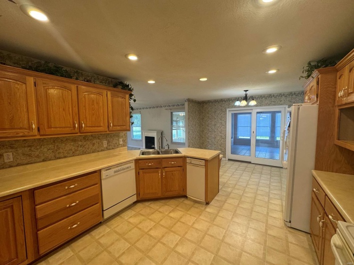 Kitchen with white appliances, sink, kitchen peninsula, pendant lighting, and a chandelier